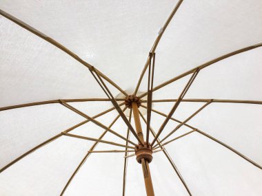 Güneş ışığı kapatmak için ahşap yapılmış beyaz plaj şemsiyesi yapısını korumalı