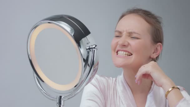 Caucasian woman with mirror with ring light with no makeup look examine her skin and makes facial treatment — Stock Video