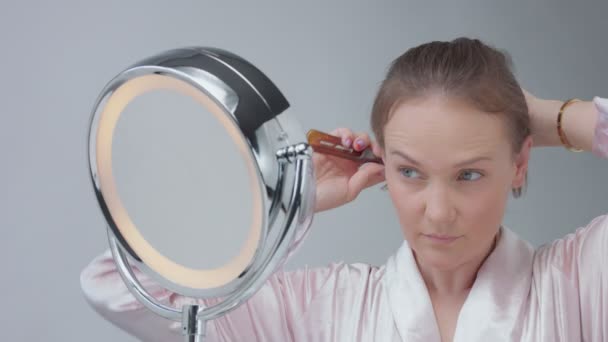 Caucasian woman with mirror with ring light with no makeup look examine her skin and makes facial treatment — Stock Video
