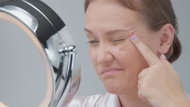 Біла жінка з дзеркалом з кільцевим світлом без макіяжу оглядає її шкіру і робить лікування обличчя — стокове відео