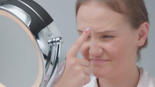 Mujer caucásica con espejo con anillo de luz sin maquillaje mirada examinar su piel y hace tratamiento facial — Vídeo de stock