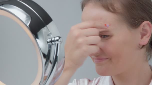 Καυκάσιος γυναίκα με καθρέπτη με φως δαχτυλιδιών με καμία εμφάνιση μακιγιάζ εξετάζει το δέρμα της και κάνει θεραπεία προσώπου — Αρχείο Βίντεο