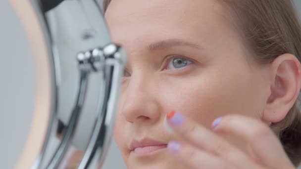 Белая женщина с зеркалом с кольцом света без макияжа взгляд изучить ее кожу и делает уход за лицом — стоковое видео
