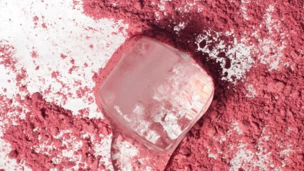 Melting cube of ice onn pink makeup powder — Stock Video