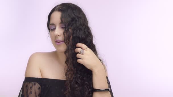 Schwarze lockige Haare plus Modell mit braunen Augen auf fliederfarbenem Hintergrund mit fliederfarbenem Make-up — Stockvideo