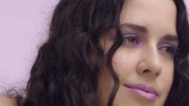 Svart lockigt hår plus storlek modell med bruna ögon på lila bakgrund med lila makeup — Stockvideo
