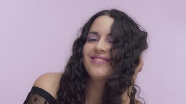 Schwarze lockige Haare plus Modell mit braunen Augen auf fliederfarbenem Hintergrund mit fliederfarbenem Make-up — Stockvideo