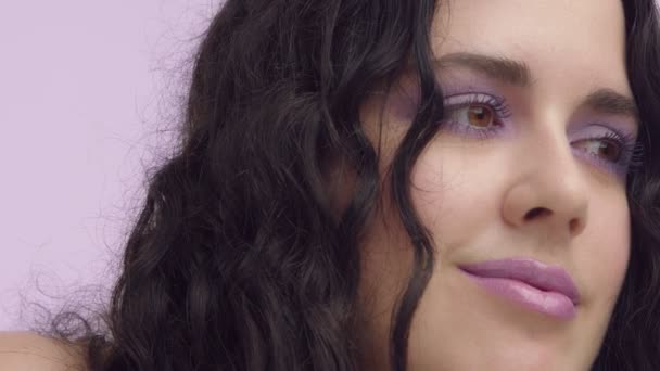 Pelo rizado negro modelo de talla grande con ojos marrones sobre fondo lila con maquillaje lila — Vídeo de stock
