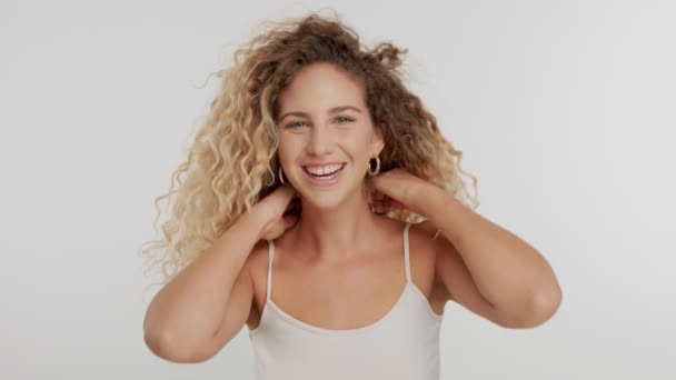 Modelo en estudio con pelo rubio rizado grande sobre blanco con maquillaje natural — Vídeo de stock