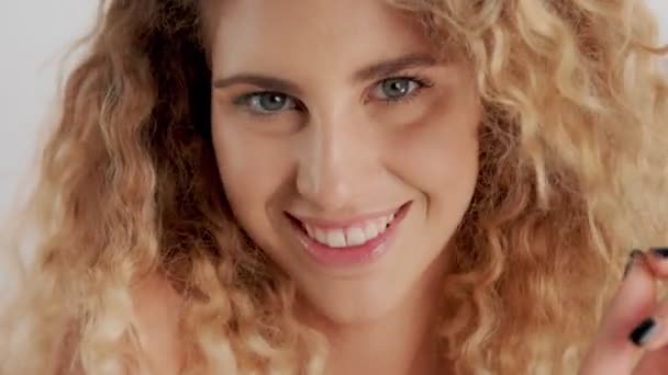 Model im Studio mit großen lockigen blonden Haaren auf weißem Hintergrund mit natürlichem Make-up — Stockvideo
