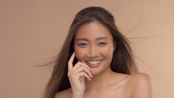 Тайська азіатська модель з натуральним макіяжем на бежевому фоні — стокове відео
