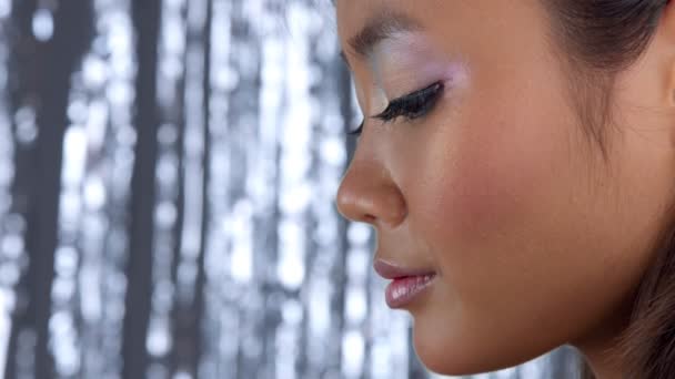 Thai asiatisk modell i studio med silver regn disco bakgrund och festmakeup — Stockvideo