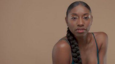 Doğal tarafsız makyaj ile bej renkli arka plan üzerinde siyah karışık ırk modeli