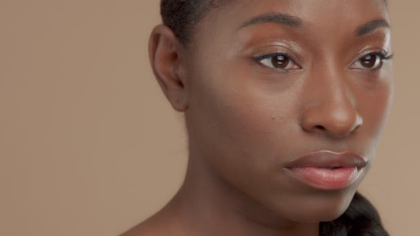 Черная смешанная расовая модель на бежевом фоне с натуральным нейтральным макияжем — стоковое видео