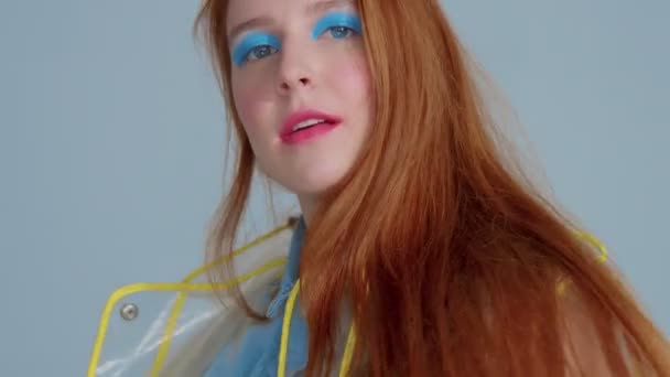 Mujer de pelo jengibre en impermeable transparente con el arte pop brillante maquillaje baile — Vídeo de stock