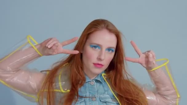 Mujer de pelo jengibre en impermeable transparente con el arte pop brillante maquillaje baile — Vídeo de stock