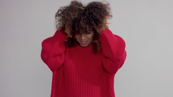 Змішана раса чорна жінка в студії з великим кучерявим волоссям потрясе його повільним рухом — стокове відео