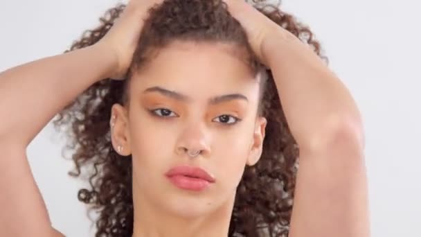 Mixte race femme noire avec des taches de rousseur et les cheveux bouclés en studio sur pose blanche à une caméra — Video