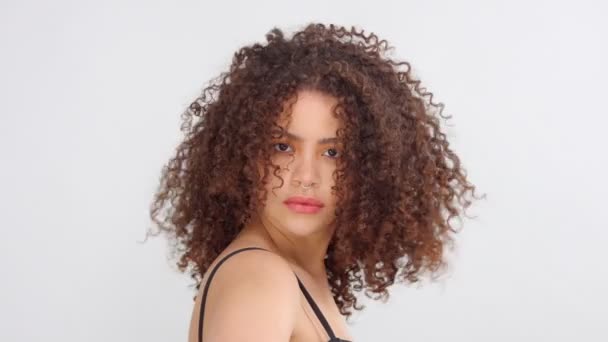 Mixte race femme noire avec des taches de rousseur et les cheveux bouclés en studio sur pose blanche à une caméra — Video