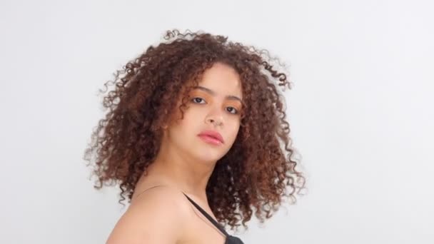 Mixte race femme noire avec des taches de rousseur et les cheveux bouclés en studio sur pose blanche à une caméra — Video