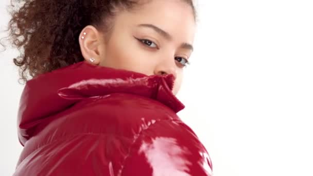 Young woman with red lacquer lips and red shiny jacket on white in studio — Stock Video