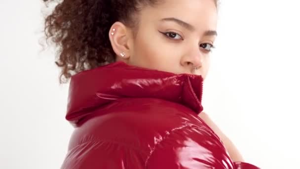 Jonge vrouw met rode lak lippen en rode glanzende jasje op wit in de studio — Stockvideo