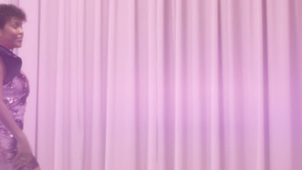 Svart blandad ras kvinna med kort frisyr och lockigt naturliga hår bär paljett glittrig klänning i rosa — Stockvideo