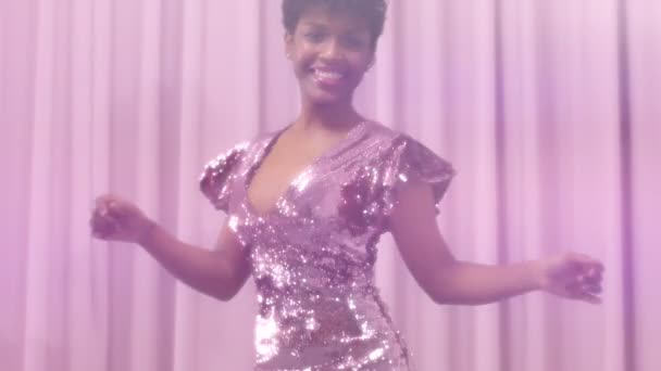 Zwart gemengd ras vrouw met kort kapsel en natuurlijke krulhaar draagt sequin sparkly jurk in roze — Stockvideo