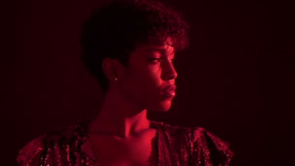 Vrouw in sparkly jurk in rood licht in nachtclub — Stockvideo