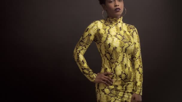 Mujer afroamericana de raza mixta en vestido amarillo brillante con estampado de pitón. Estilo de los años 90 — Vídeos de Stock