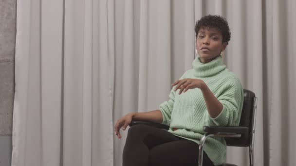 Жінка в м'ятному светрі в студії з сірим фоном завіси, стиль депресії 90-х — стокове відео