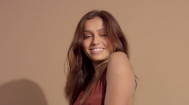 genç ve güzel modeli gülümseyen ve kameraya, üfleme saç izlerken Studio