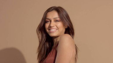 genç ve güzel modeli gülümseyen ve kameraya, üfleme saç izlerken Studio