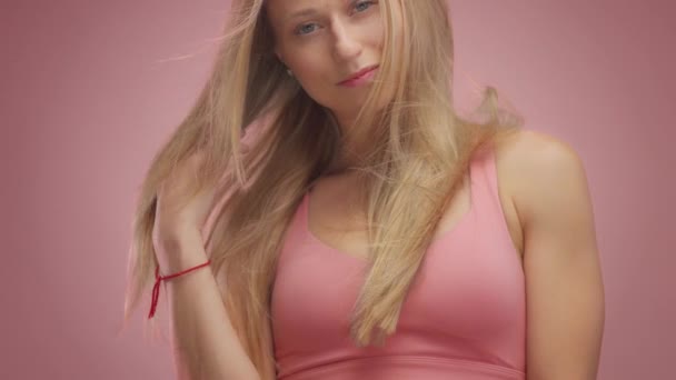 Blond model in Studio op roze achtergrond met haar waait in de lucht — Stockvideo