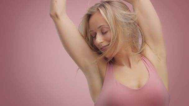 Blond modelka w Studio na różowym tle z włosami dmuchanie w powietrzu — Wideo stockowe