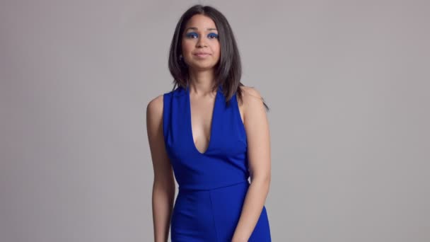 Смешанная раса молодая женщина с ярко-голубым макияжем в студии съемки в электрическом голубом платье — стоковое видео