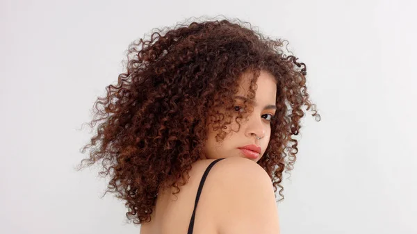 Gemengd ras zwarte vrouw met sproeten en krullend haar close-up portret met haren blazen — Stockfoto
