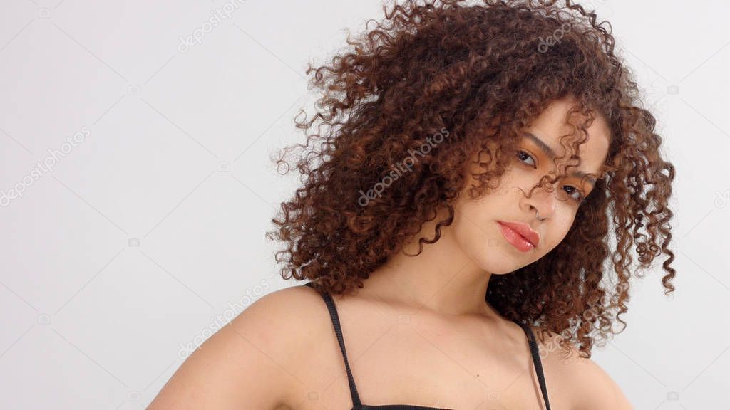 mixed race black woman with freckles and curly hair closeup portrait with hair blowing