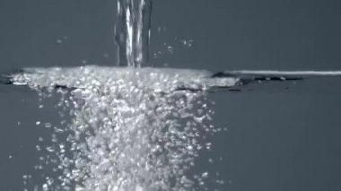 su ile şeffaf bir akvaryumda dökülen temiz su. Su sıçraması, kabarcıklar, 60 fps yavaş hareket