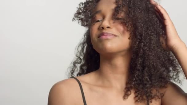 Zaostřená portrét s mladým smíšeným modelem rasy se kudrnatými vlasy ve studiu s přírodním neutrálním líčením — Stock video