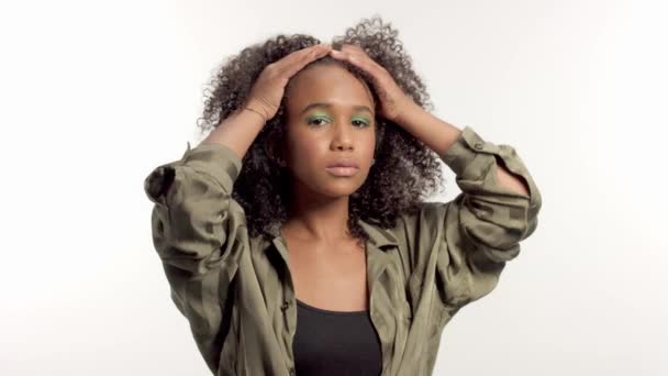 Mladý smíšený model rasy ve studiu na bílém se kudrnatými vlasy, světle zelený oční make — Stock video
