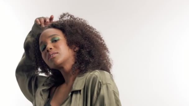 Jeune modèle mixte en studio sur blanc avec cheveux bouclés, maquillage des yeux vert vif — Video