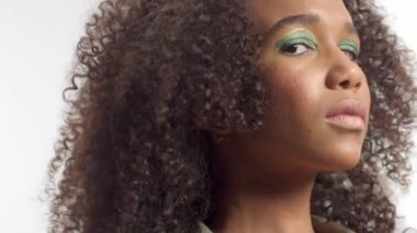 kıvırcık saçlı beyaz stüdyoda genç karışık yarış modeli, parlak yeşil göz makyajı