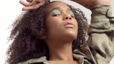 kıvırcık saçlı beyaz stüdyoda genç karışık yarış modeli, parlak yeşil göz makyajı