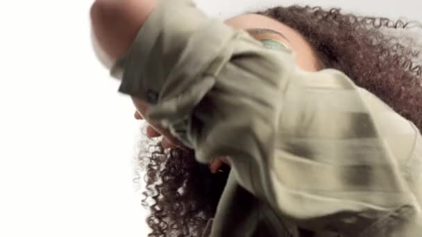 Jeune modèle mixte en studio sur blanc avec cheveux bouclés, maquillage des yeux vert vif — Video