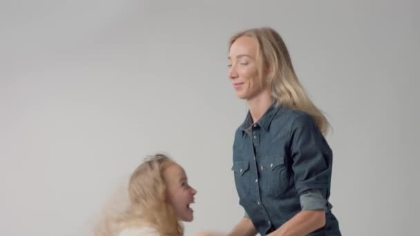 Молодая девушка прыгает на руках к маме и улыбается обеим — стоковое видео