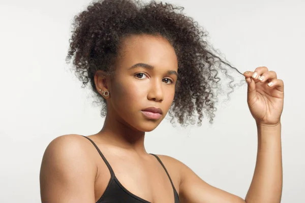 Портрет крупным планом молодой модели смешанной расы с вьющимися волосами в студии с натуральным нейтральным макияжем — стоковое фото