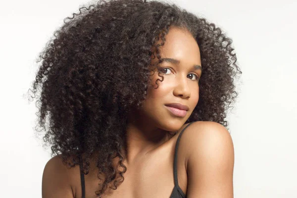 Портрет крупным планом молодой модели смешанной расы с вьющимися волосами в студии с натуральным нейтральным макияжем — стоковое фото