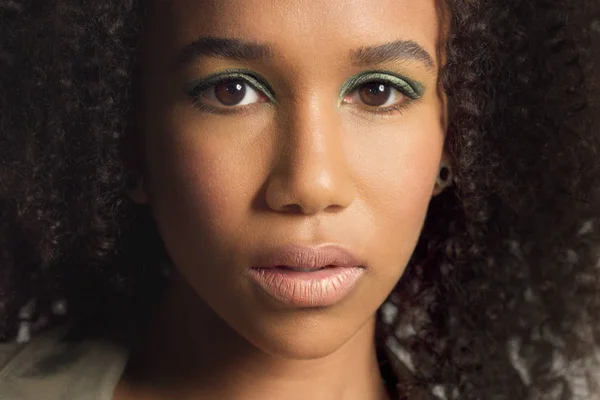 Zaostřená portrét mladého směsového modelu rasy se kudrnatými vlasy ve studiu se zelenými kovovými oční stíny — Stock fotografie