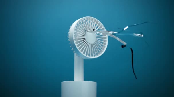 Маленький білий вентилятор зі срібними смугами, що дме — стокове відео